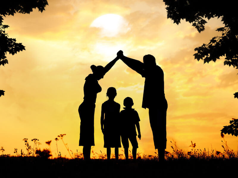 Happy family silhouette with parents and children under sunset sky representing adoption and family protection services